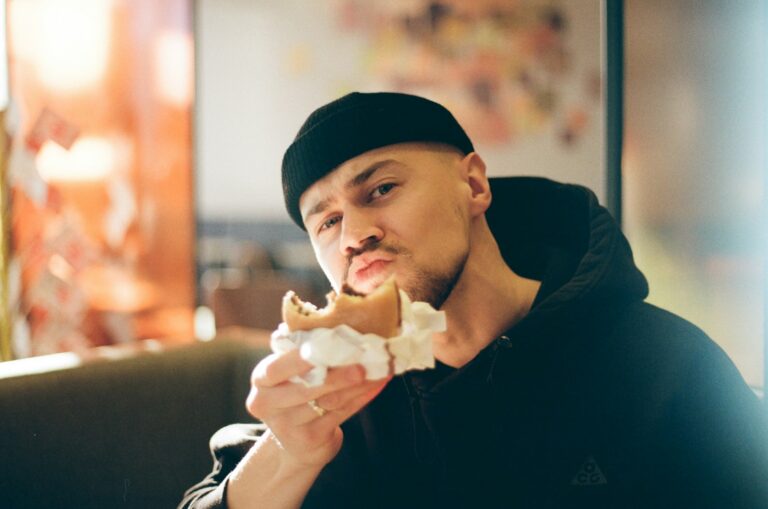 Man in black beanie eating a messy burger