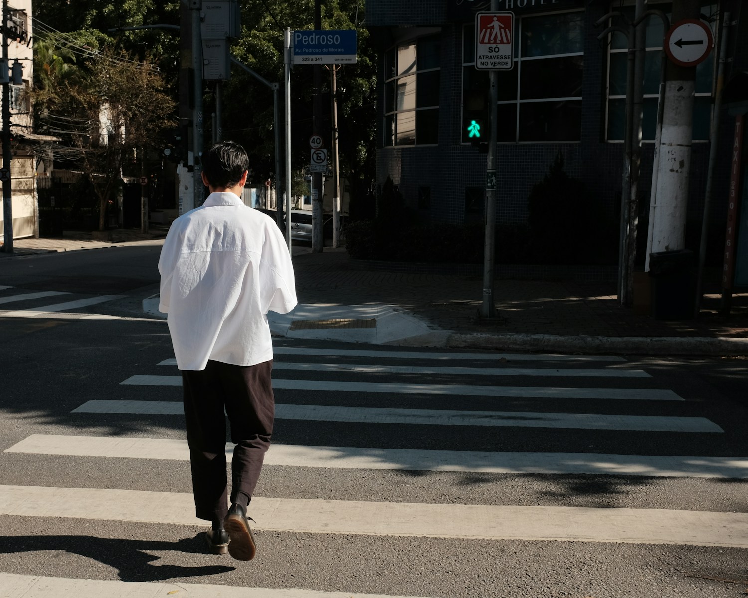 a man in a white shirt is crossing the street