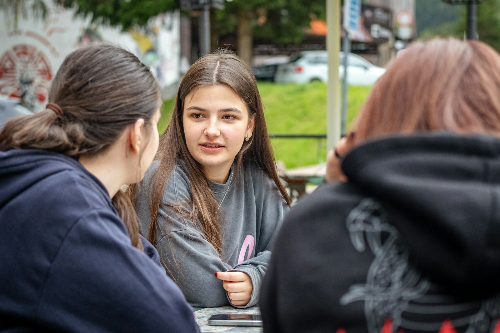 Three young women talking at an outdoor table