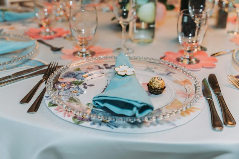 Elegant table setting with floral plates and blue napkins.