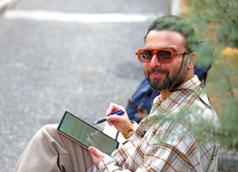 Man with sunglasses drawing on a tablet outdoors
