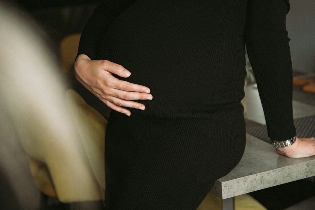 a pregnant woman standing on a stool with her hands on her stomach
