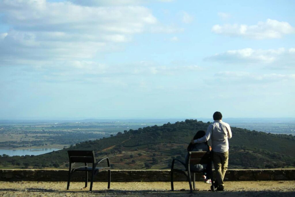 a man and a woman sitting on a bench overlooking a city