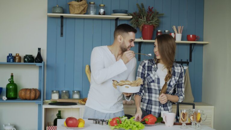Couple cooking together in a blue kitchen.
