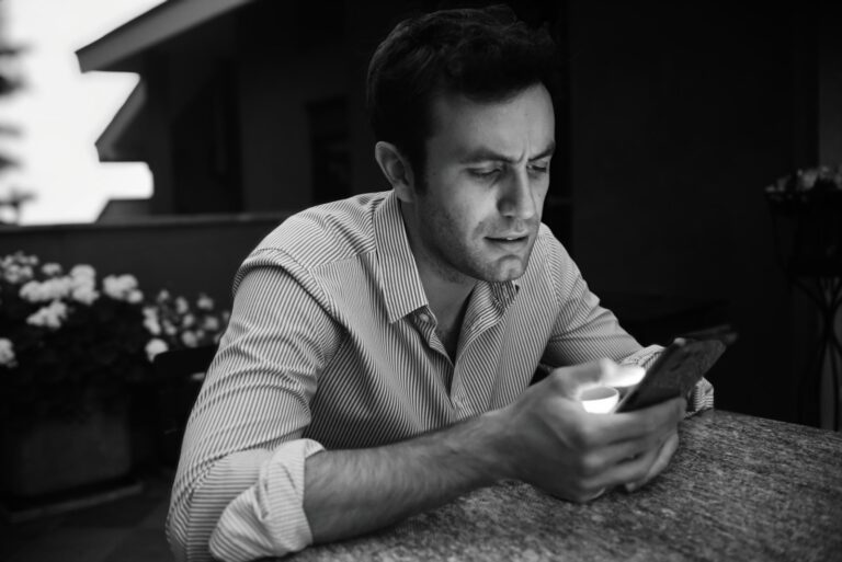 a man sitting at a table looking at a cell phone