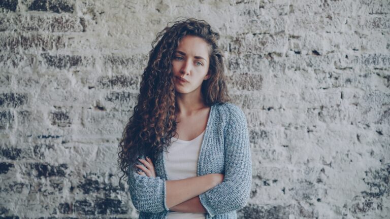Young woman with curly hair crosses arms