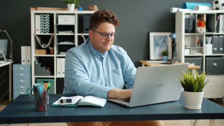 Man working on laptop at desk in office.