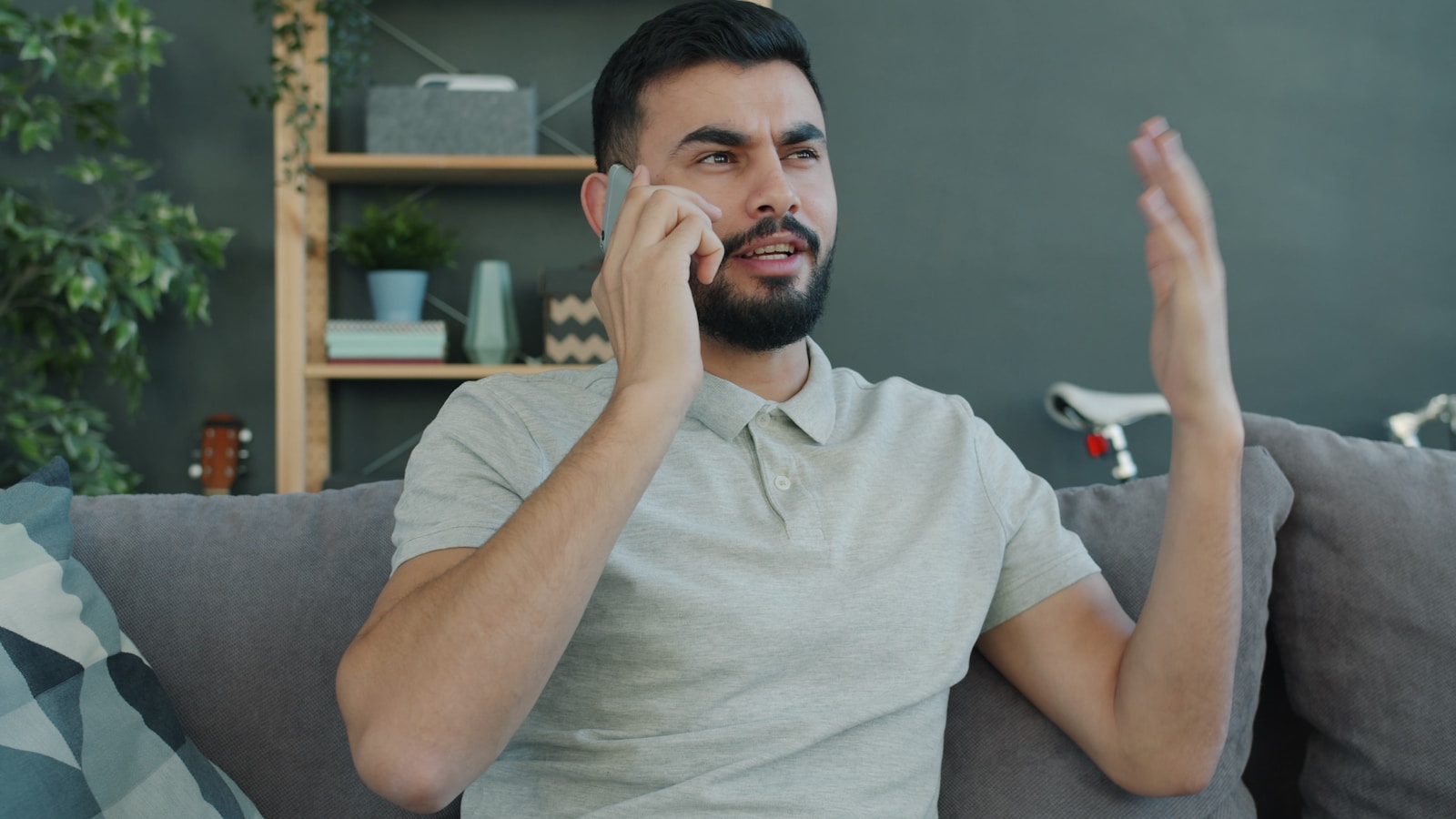 Man talking animatedly on the phone while sitting on couch.
