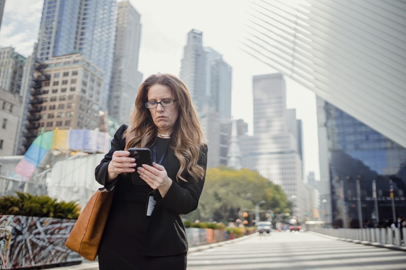 Businesswoman on phone in city street against modern skyscrapers.