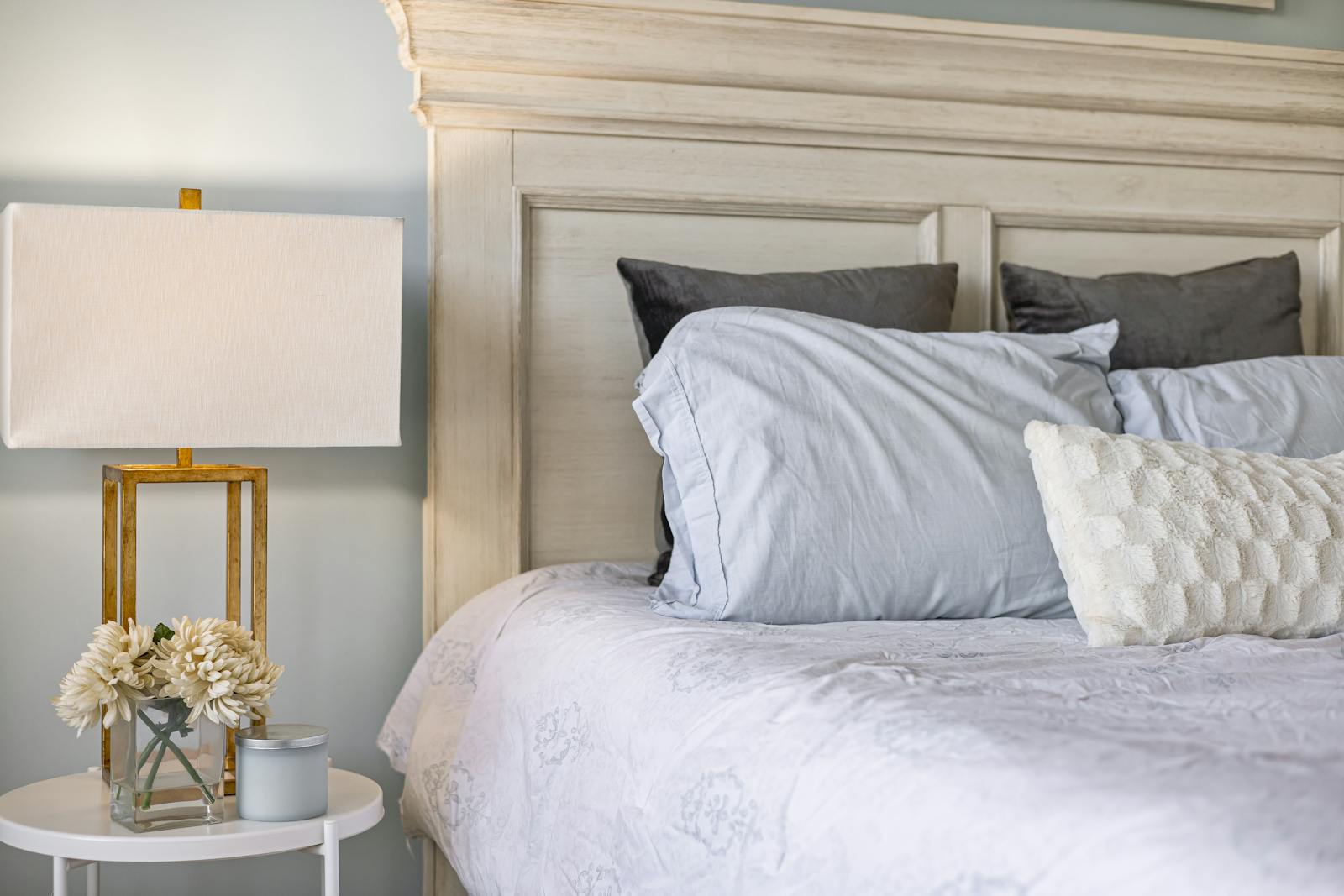 Stylish bedroom interior featuring a comfy bed, decorative pillows, and a modern lamp on a side table.