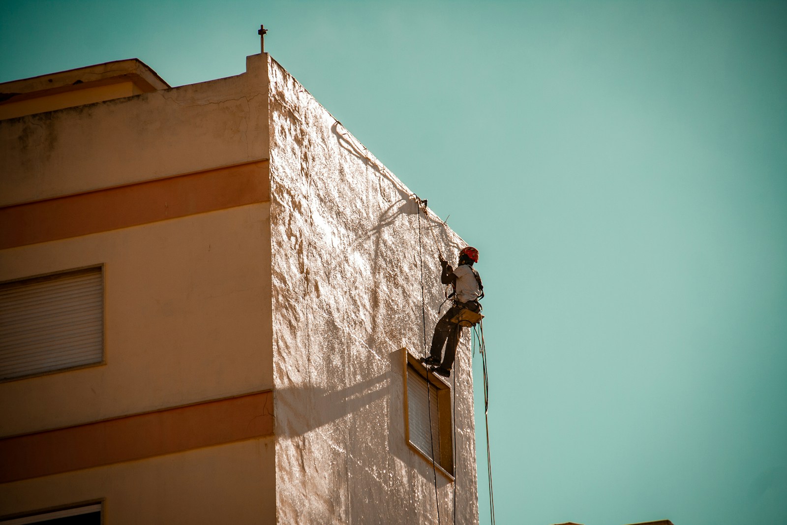 a man on a ladder working on the side of a building