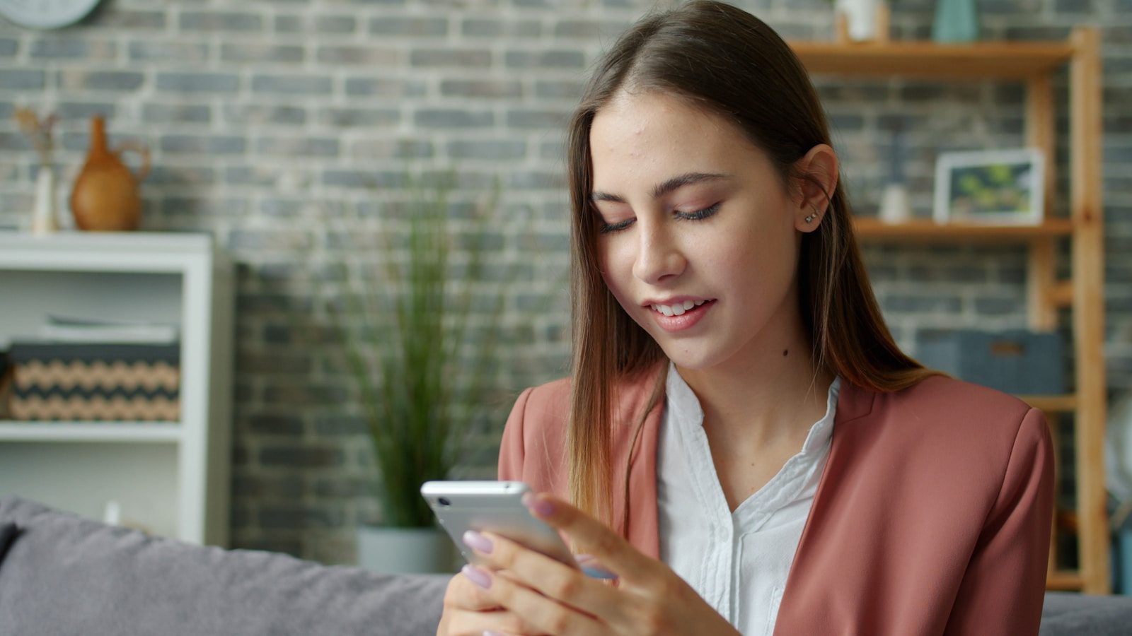 Young woman looking at her smartphone on a couch.