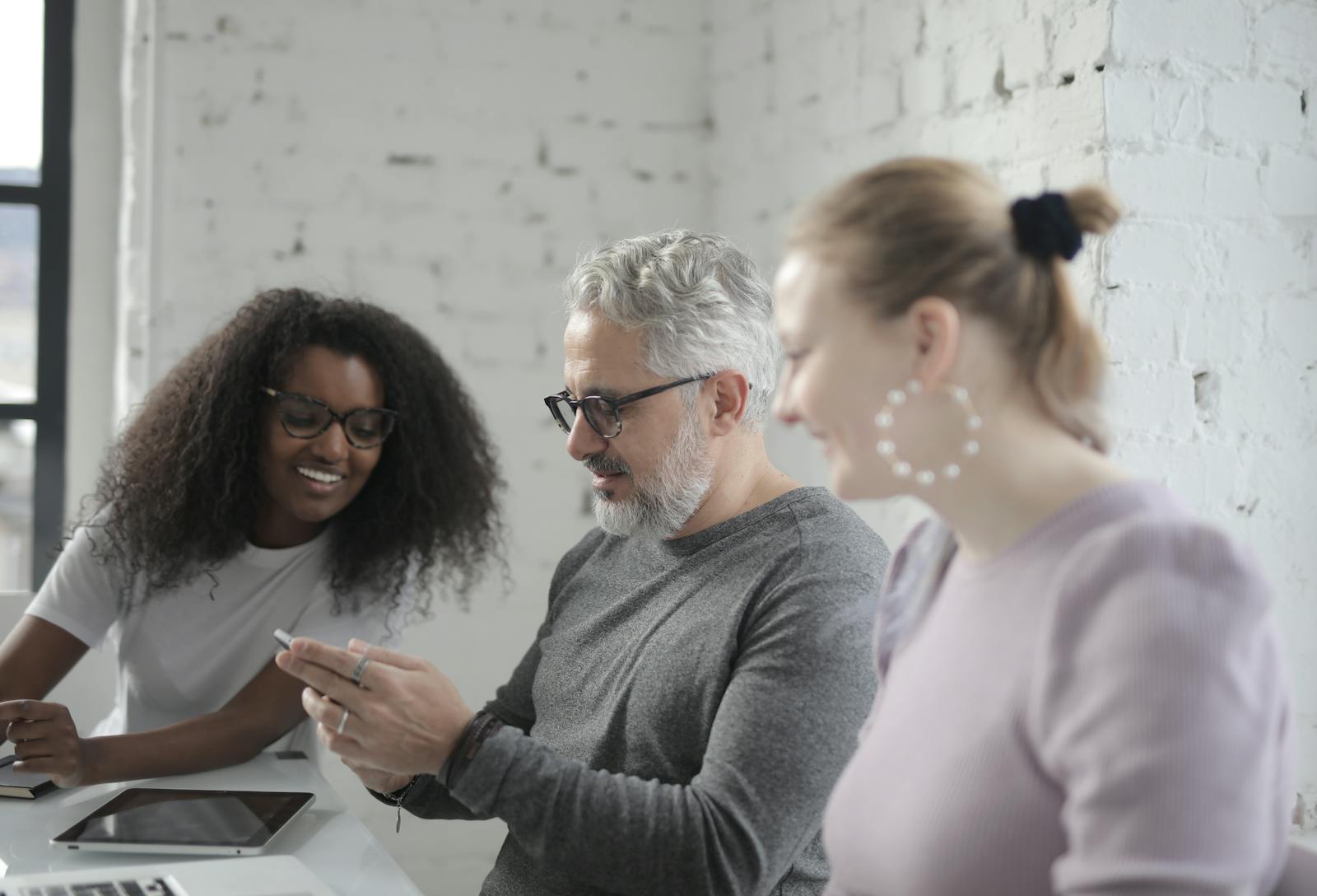 Multiracial team enjoying collaboration indoors, with focus on mobile technology.