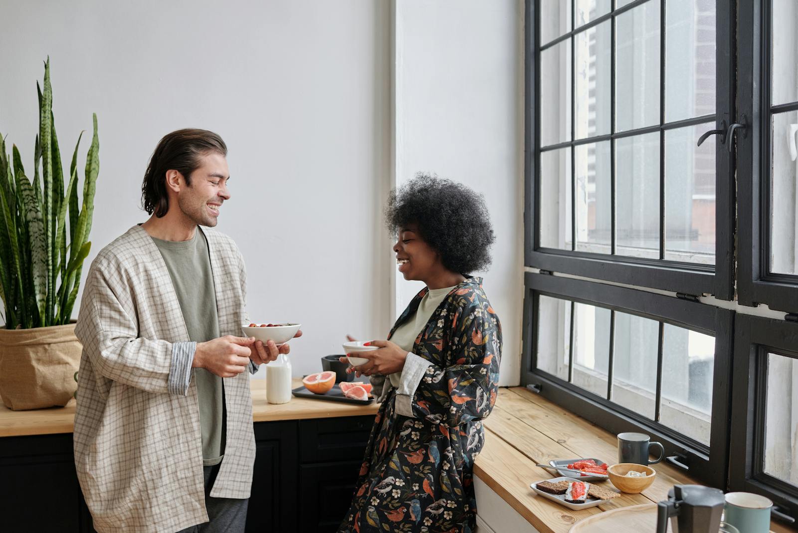 A happy couple shares a light breakfast by the window, showcasing togetherness and joy.