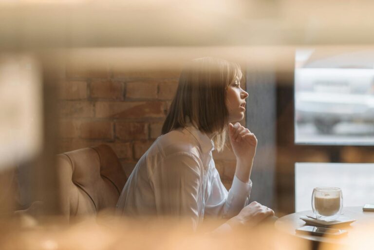 Reflective moment of a woman in a coffee shop by a window, enjoying a coffee.