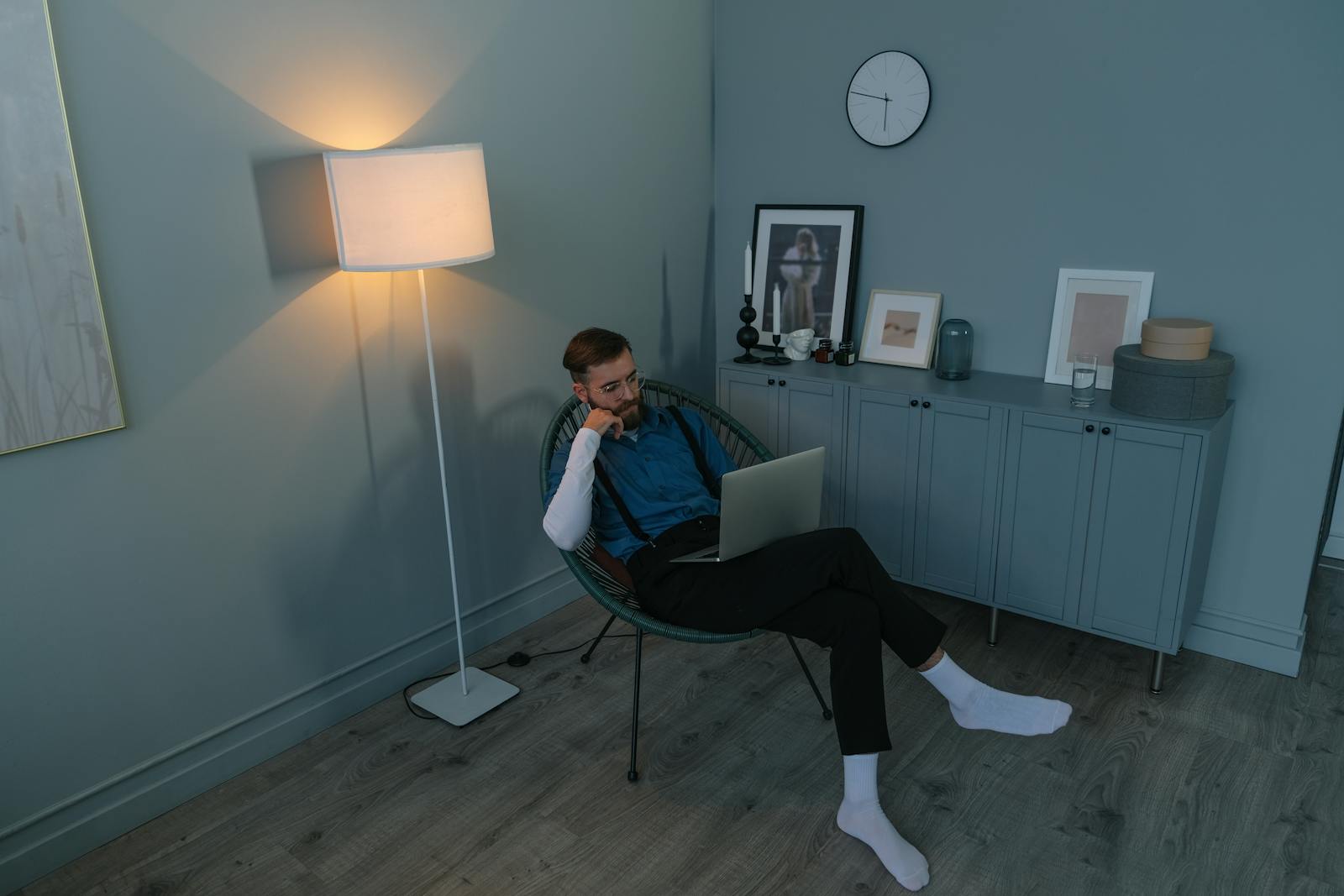 A man in a modern room sits thoughtfully with a laptop, showcasing a contemporary lifestyle.