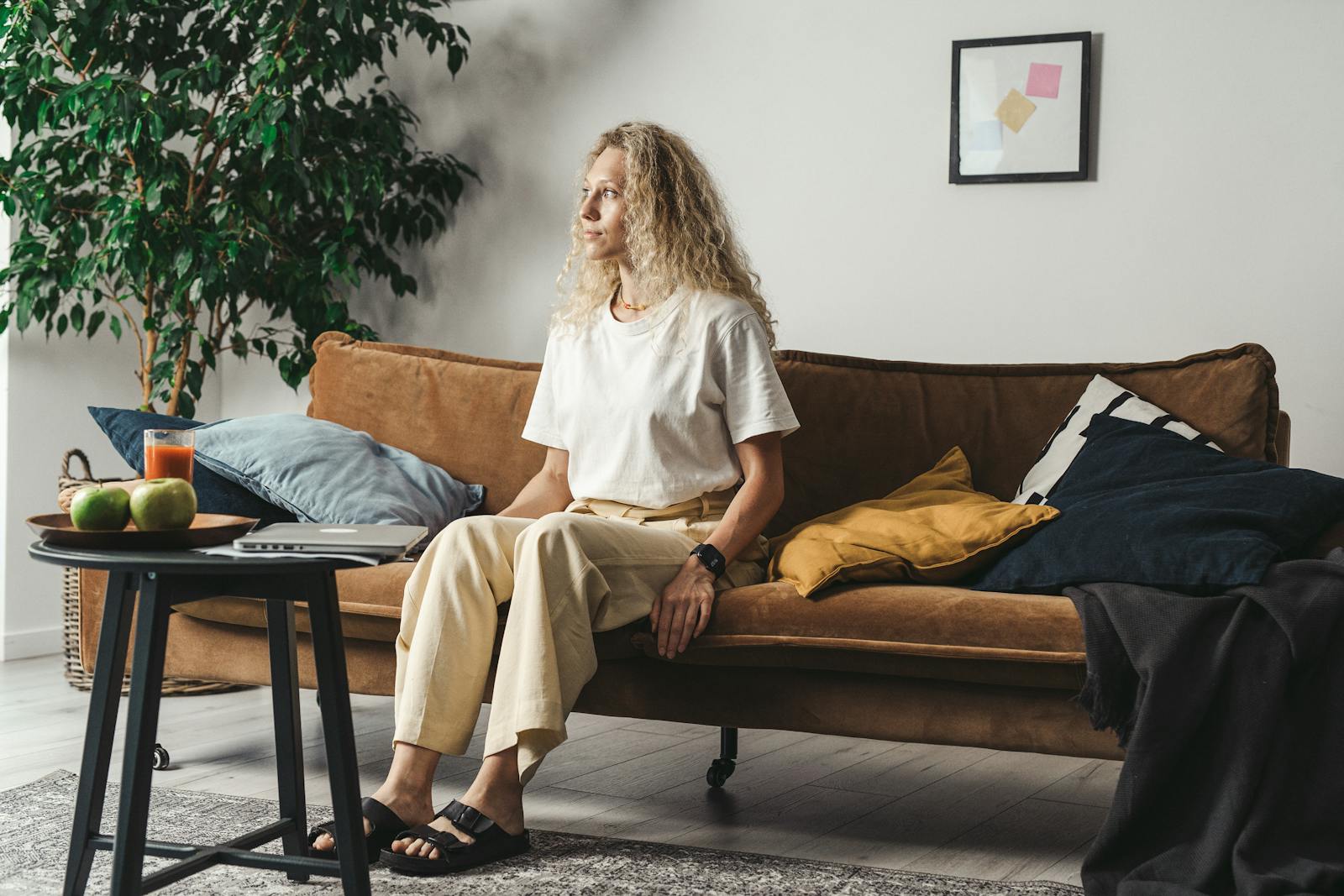 Relaxed woman sitting on a couch in a cozy, stylish living room.