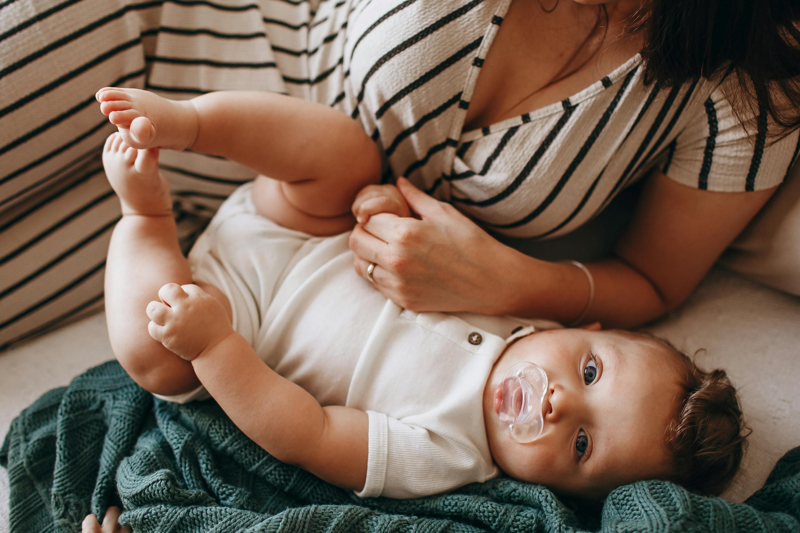 A close-up portrait of a mother holding her baby indoors in a relaxed setting, showcasing warmth and affection.