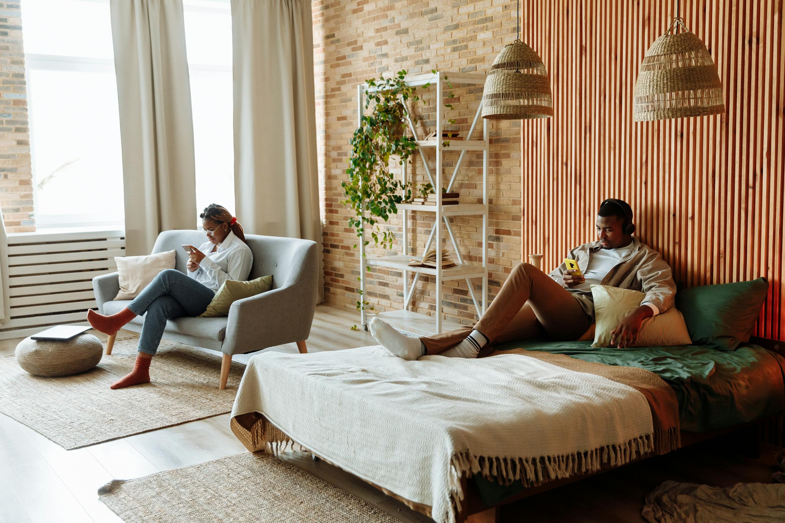 A couple relaxing with gadgets in a stylish loft bedroom with natural decor.