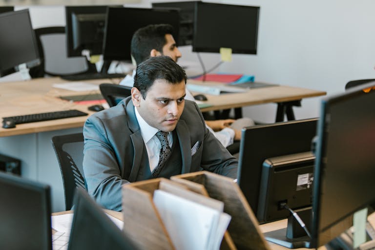 A dedicated businessman in a suit concentrating on work at a modern office desk.