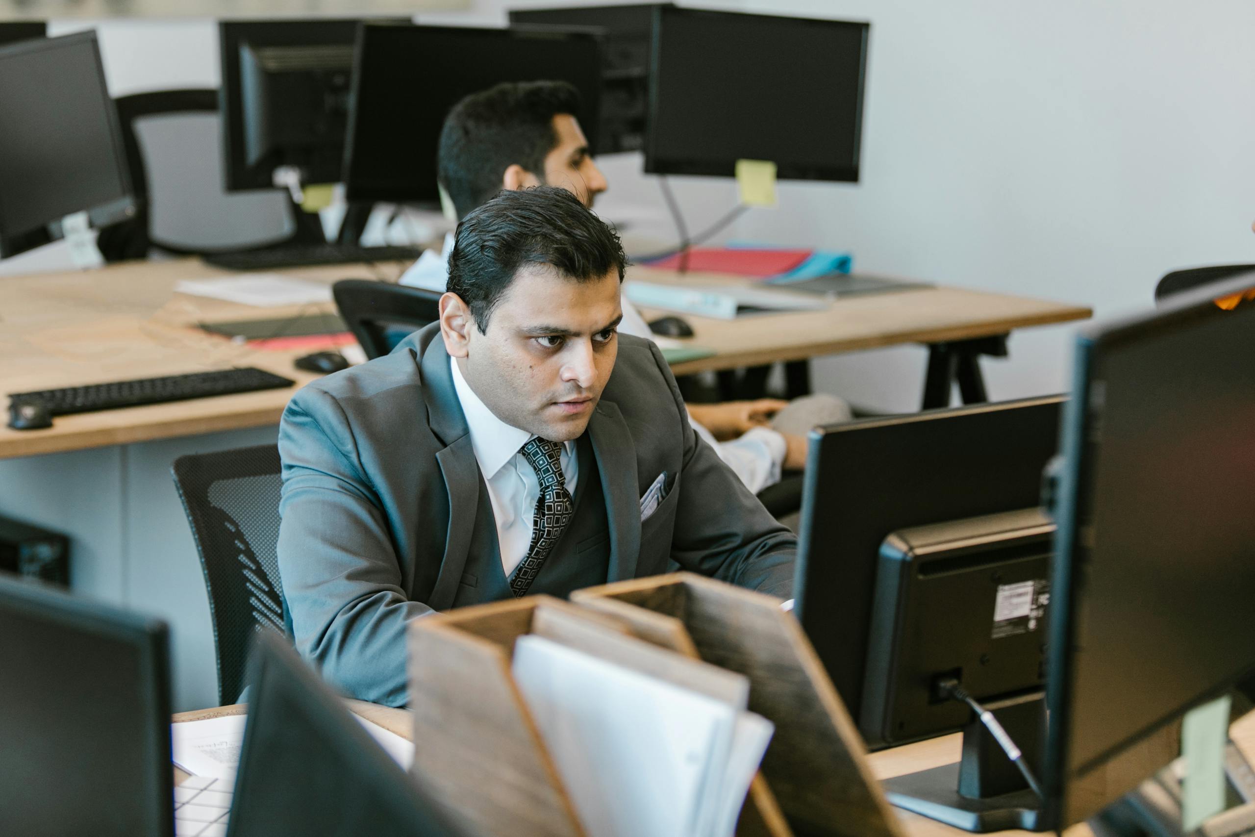 A dedicated businessman in a suit concentrating on work at a modern office desk.
