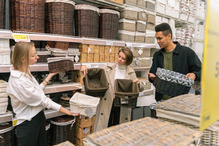 A diverse group of adults selecting wicker baskets in a retail store aisle.