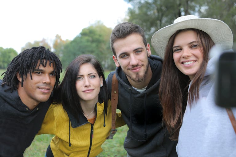 A diverse group of friends enjoying a fun day outdoors taking a selfie in the park.