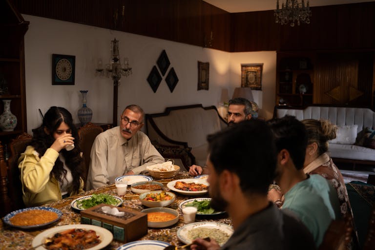 A family enjoys a traditional meal around a dining table in a warmly lit living room.