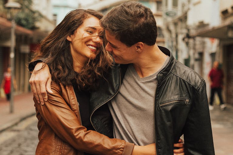 A joyful couple embracing and smiling on a city street, capturing love and happiness.