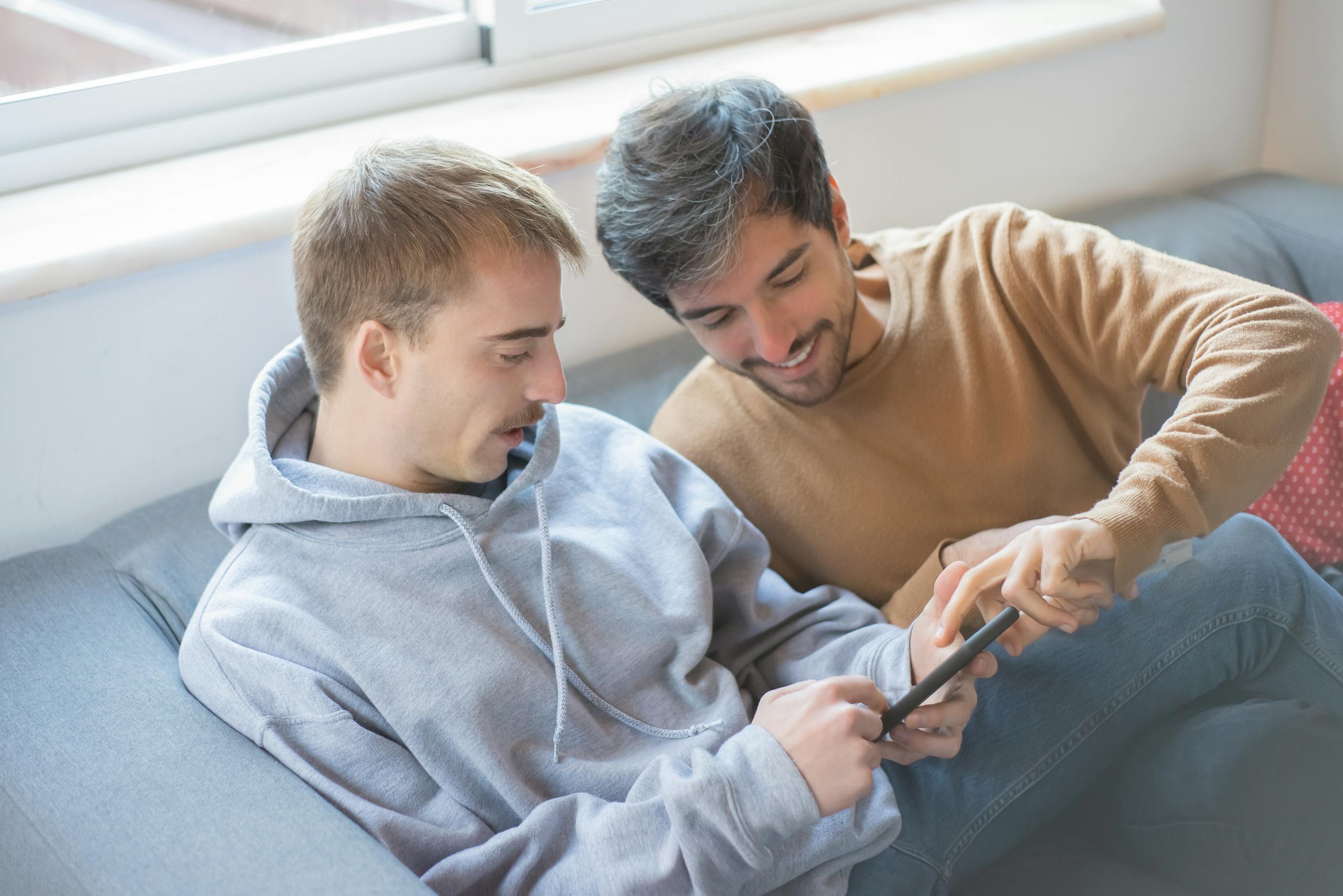 A joyful moment of a couple using a smartphone on a cozy couch. Perfect for technology and relationship themes.