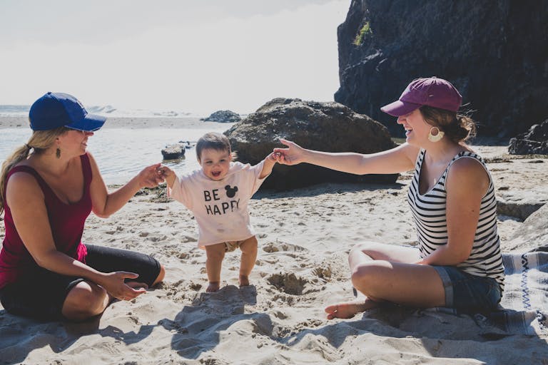 A joyful scene of a baby playing with two women on Rockaway Beach. Capturing happiness.