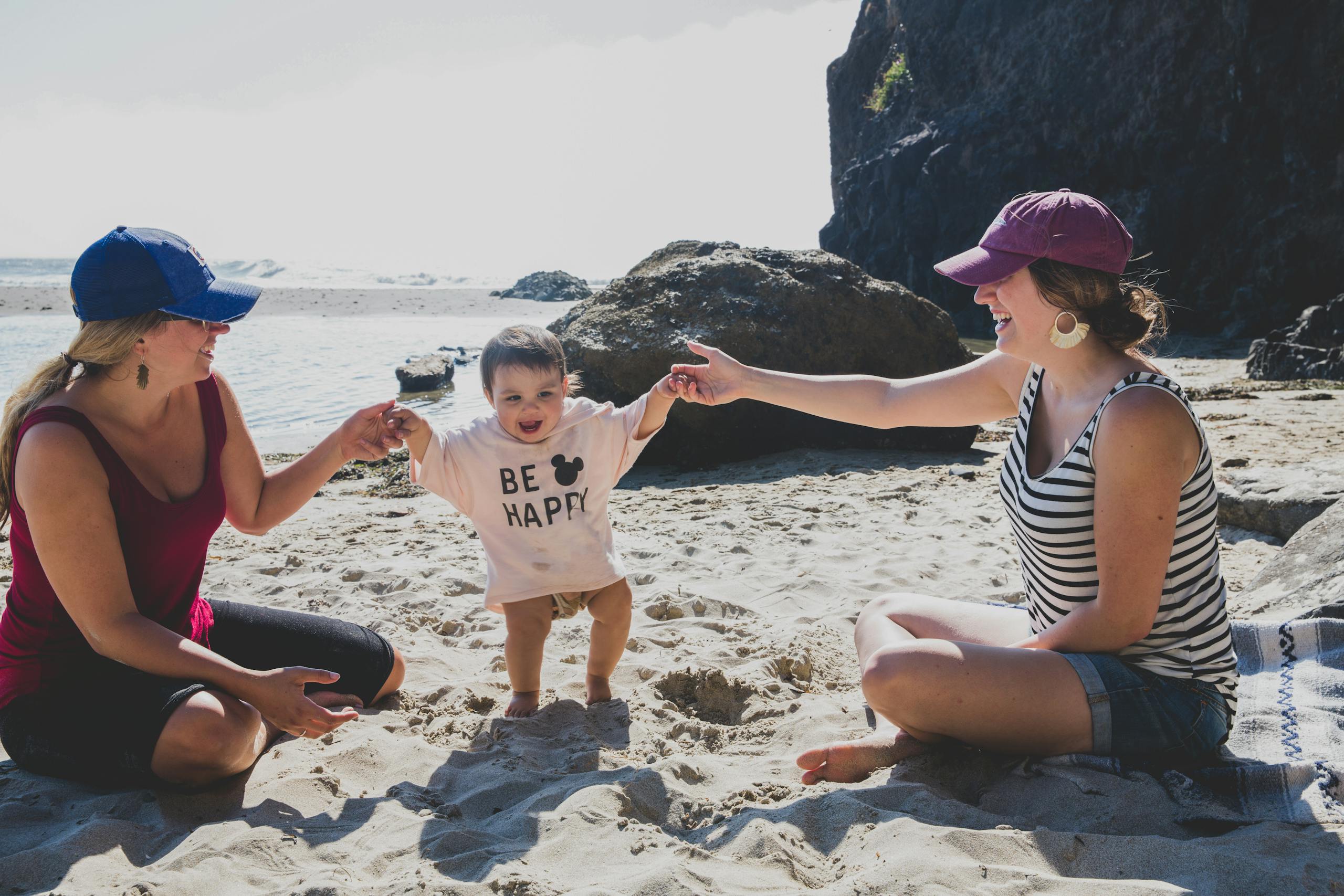A joyful scene of a baby playing with two women on Rockaway Beach. Capturing happiness.
