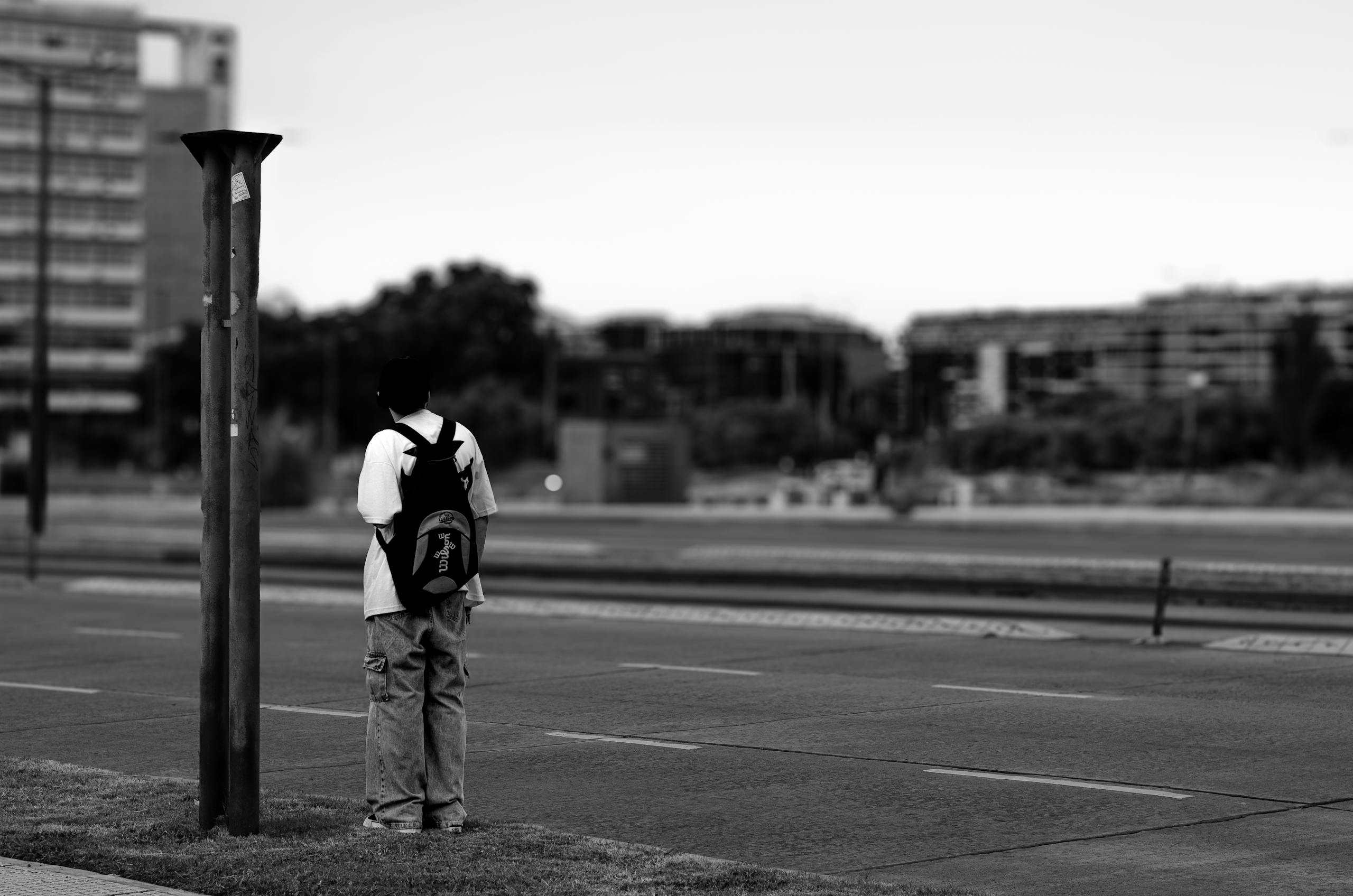 A lone figure with a backpack stands on an urban street, creating a moody city scene.