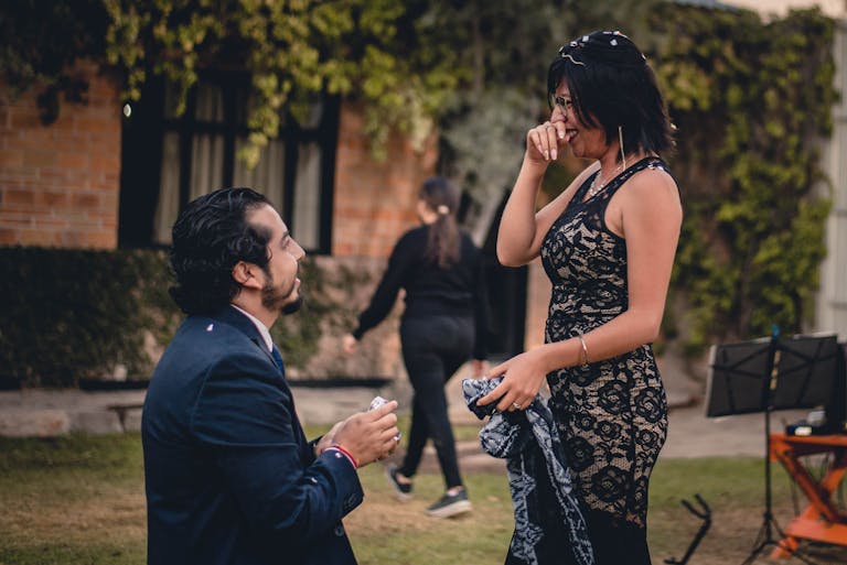 A man proposes to a woman in a garden, capturing a beautiful engagement moment.
