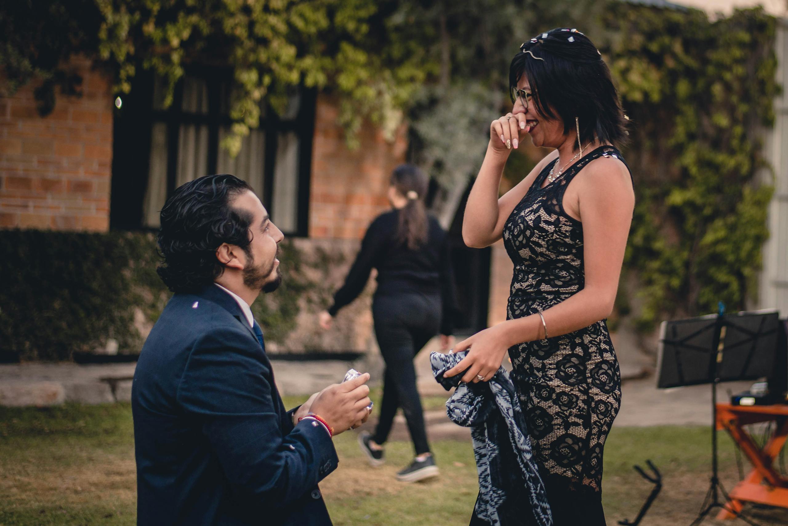A man proposes to a woman in a garden, capturing a beautiful engagement moment.