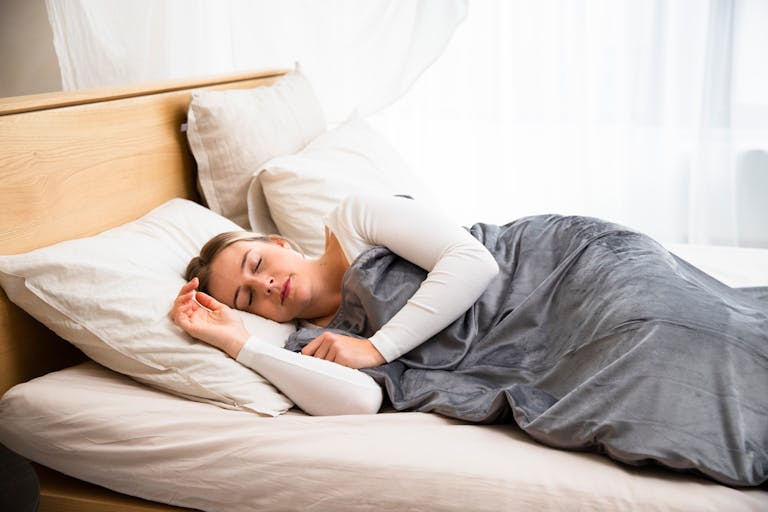 A serene portrait of a woman sleeping comfortably in a cozy bedroom setting, highlighting relaxation.