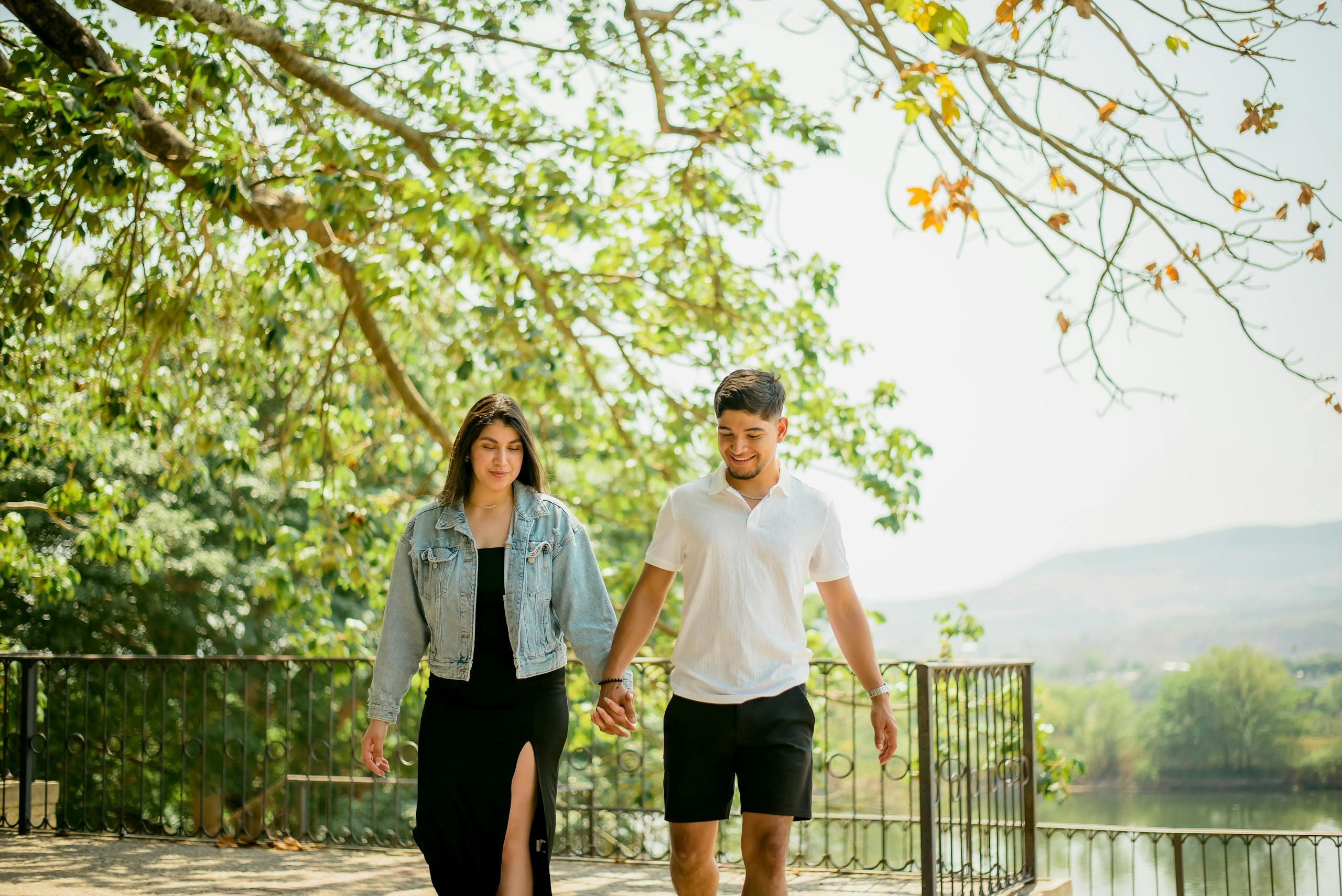 A young couple enjoying a sunny day, holding hands while walking outdoors.