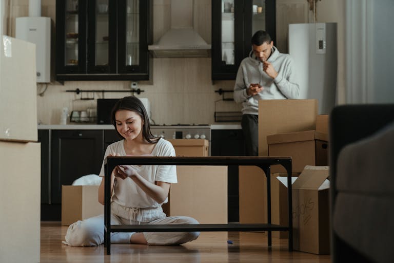 A young couple unpacking boxes in their new apartment kitchen, settling into a cozy home.