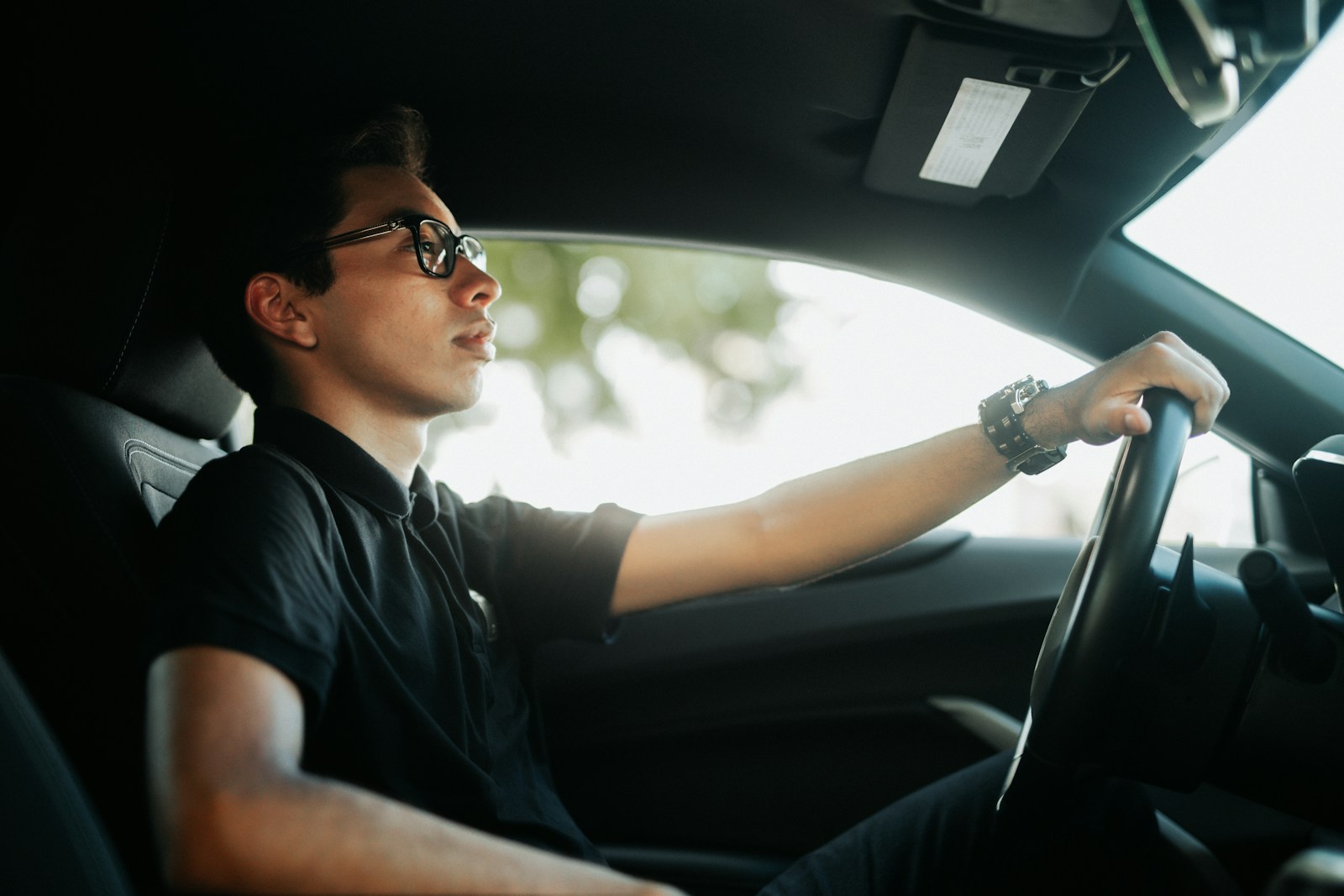 a man driving a car with his hand on the steering wheel