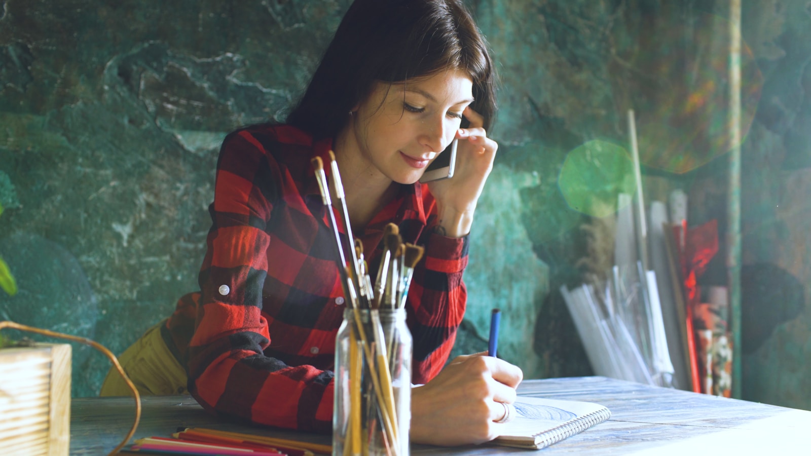 Young woman in red plaid shirt writing in notebook
