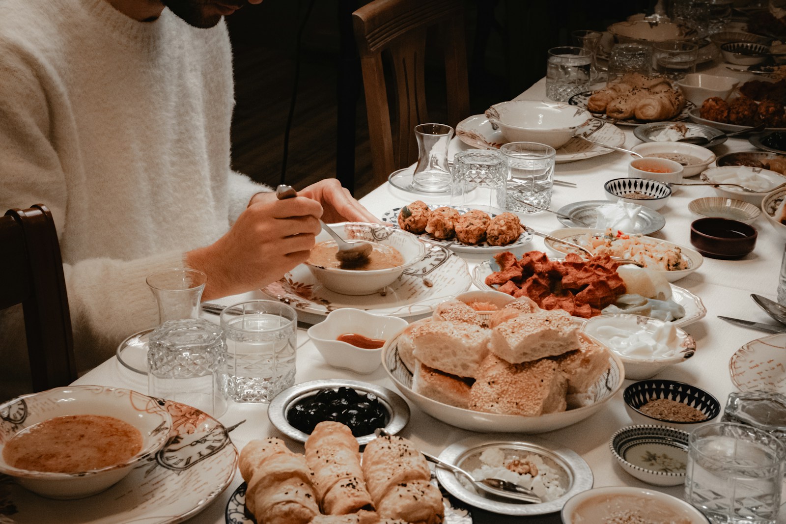 A person eating at a table full of food.