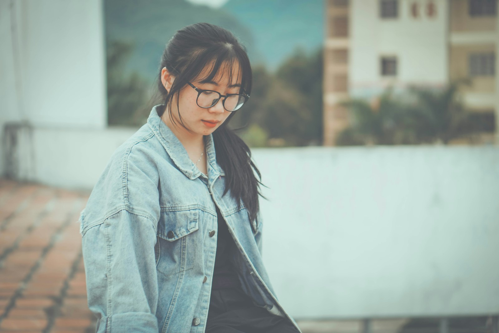 a woman wearing glasses and a denim jacket