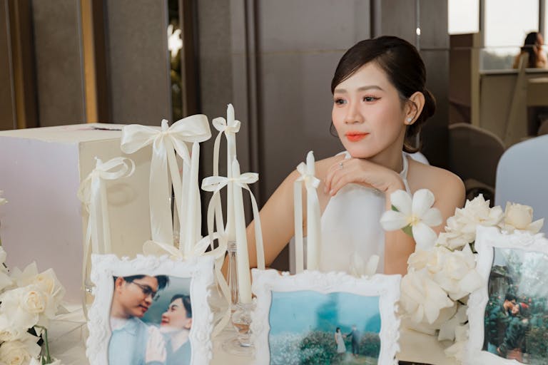 Bride at a wedding reception table adorned with candles and photos.