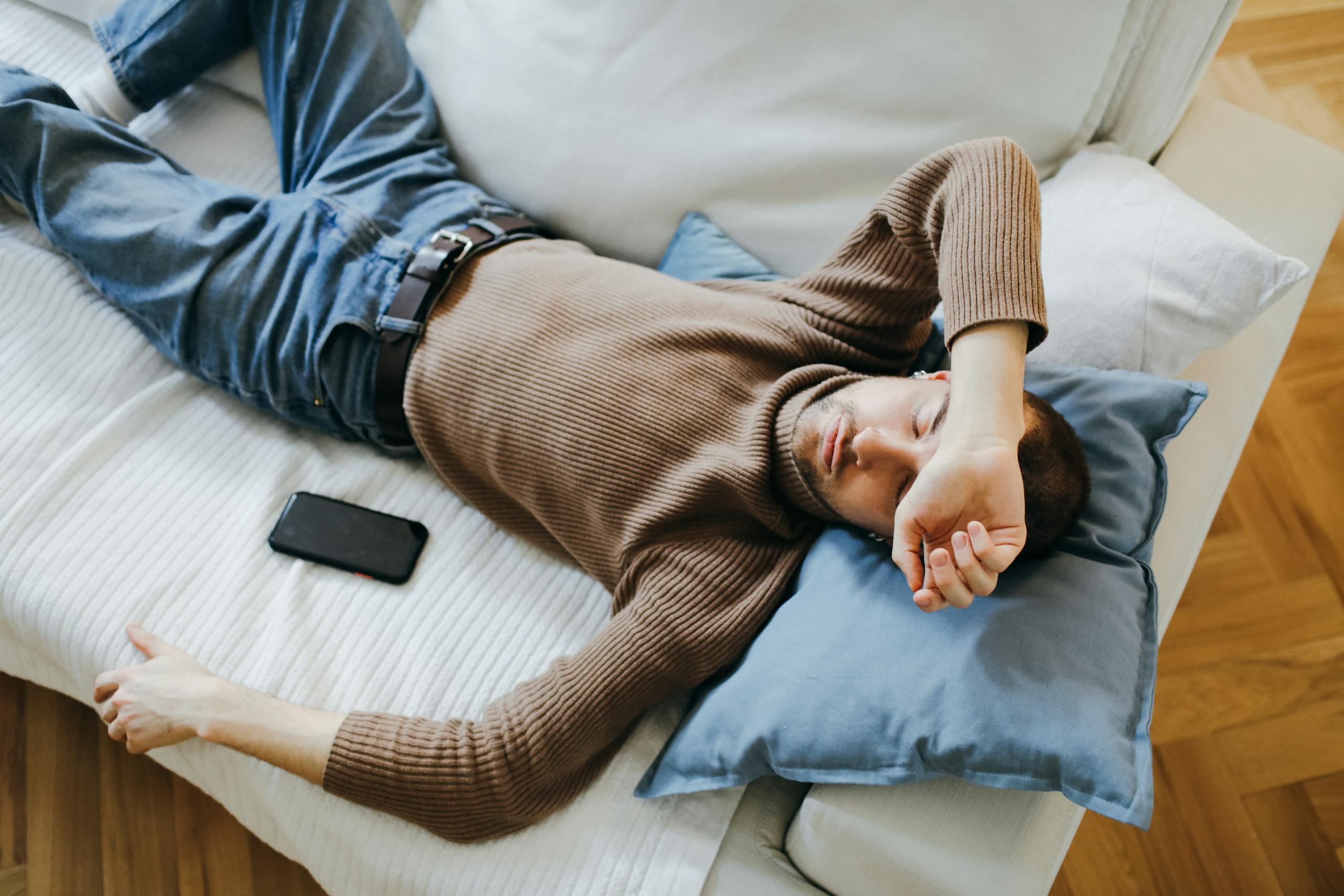 Casual man resting on a sofa at home, illustrating tranquility and relaxation.