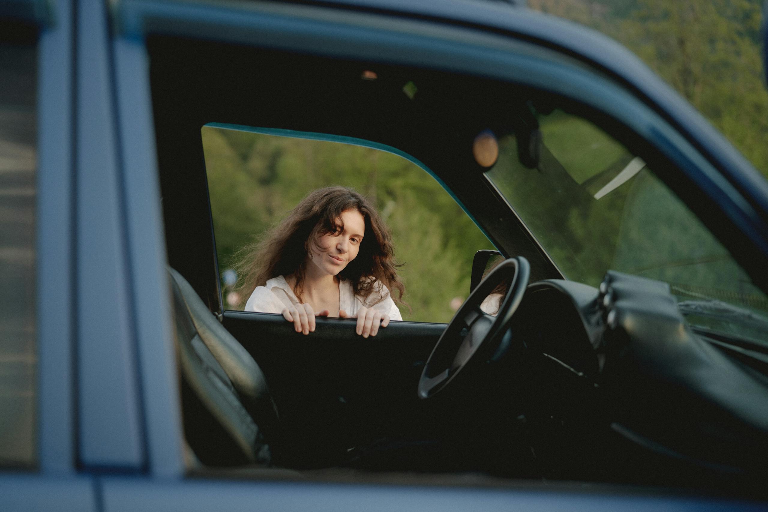 Caucasian woman smiling through car window outdoors. Relaxing and nature scene.