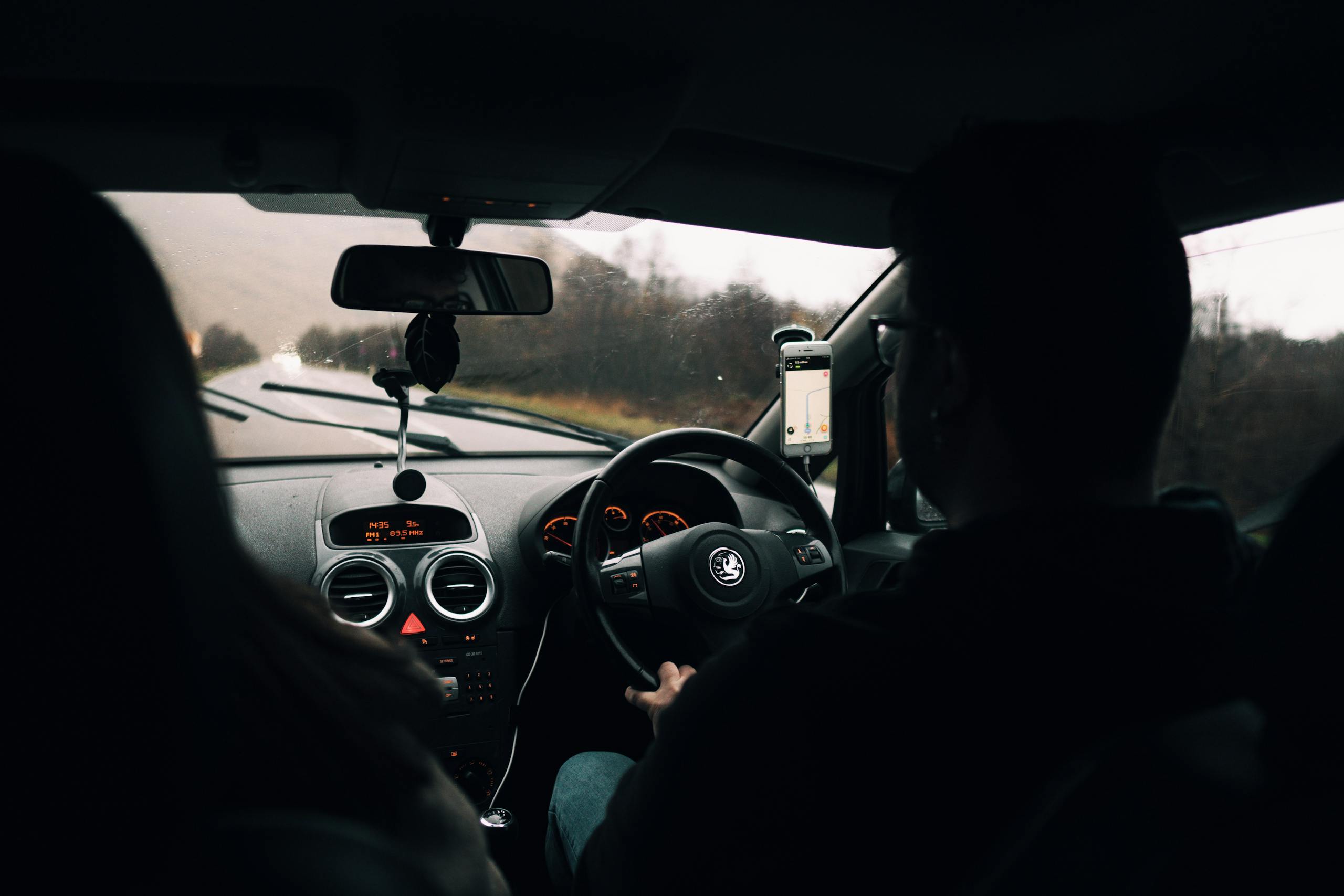 Couple driving through scenic Scottish countryside on a rainy day, inside car view.