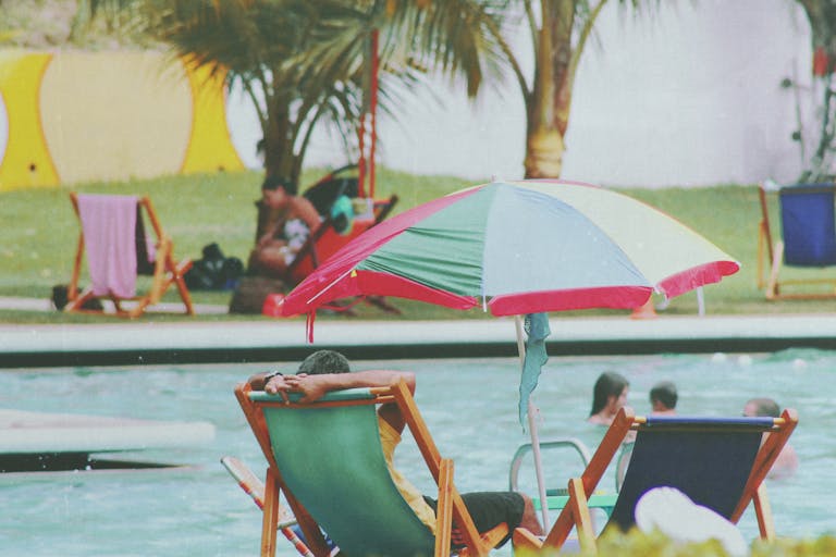 Deck chairs and umbrellas by a vibrant pool, perfect for summer relaxation.