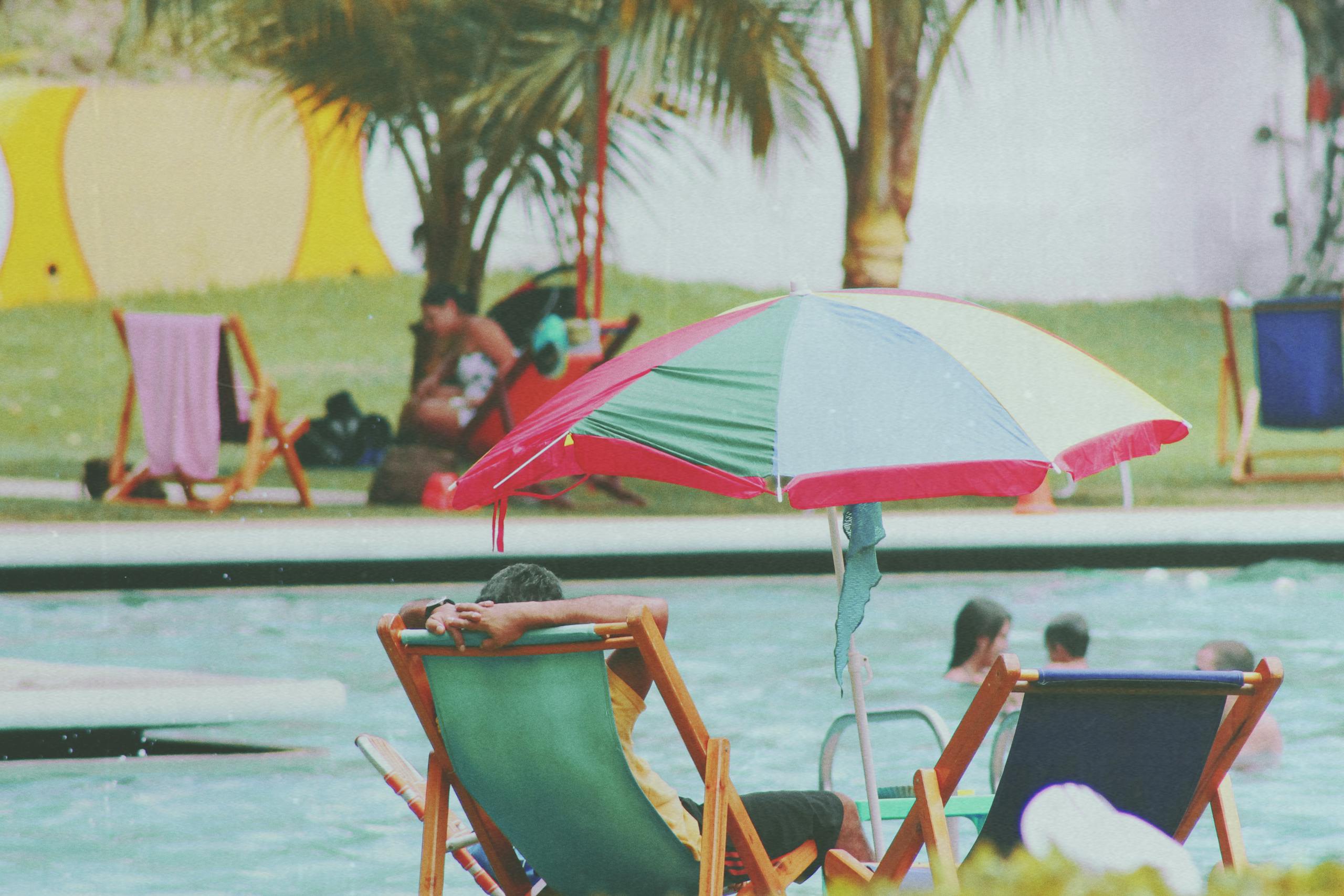 Deck chairs and umbrellas by a vibrant pool, perfect for summer relaxation.