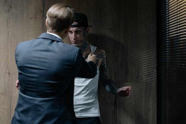 Detective interrogating a tattooed suspect in a dimly lit room, evoking suspense.