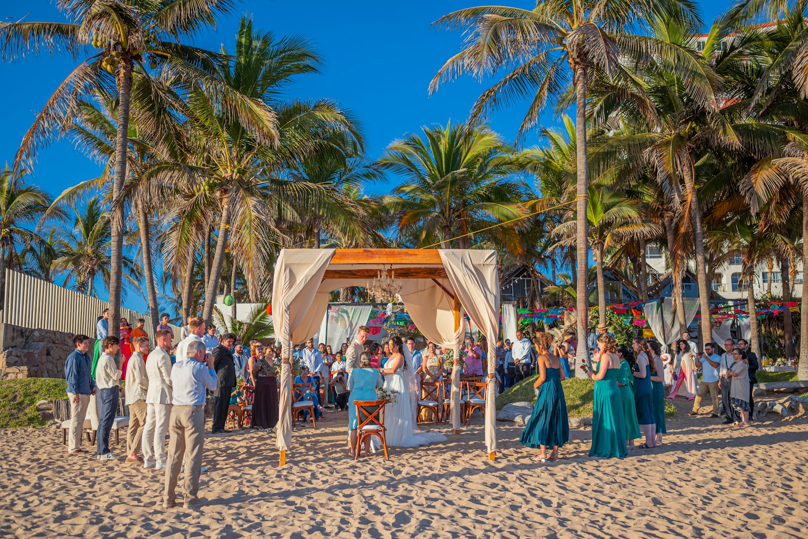 Wedding ceremony on a sandy beach with palm trees.